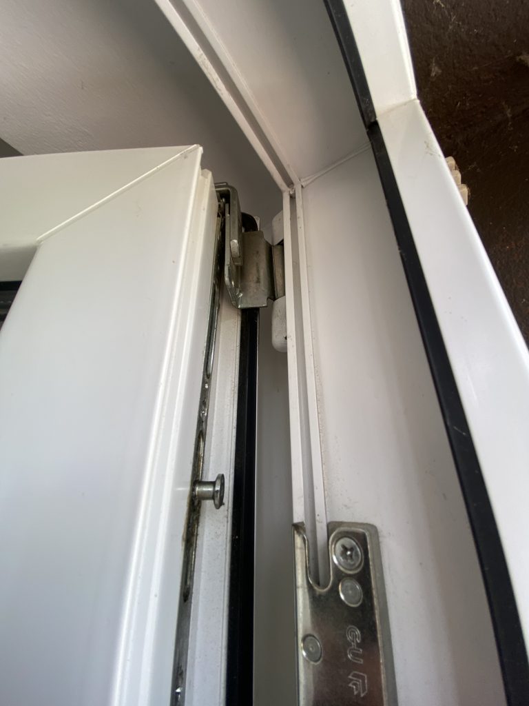 Weißes Kunststofffenster. Geöffnet mit Sicht auf die Fensterbeschläge